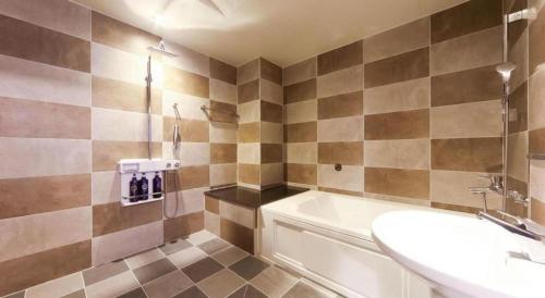 a bathroom with a toilet and a sink and a tub at H Hotel in Ulsan