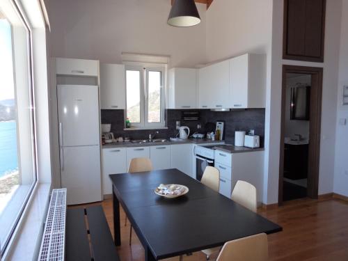 a kitchen with white cabinets and a black table and chairs at Lefka's Villas in Vivari