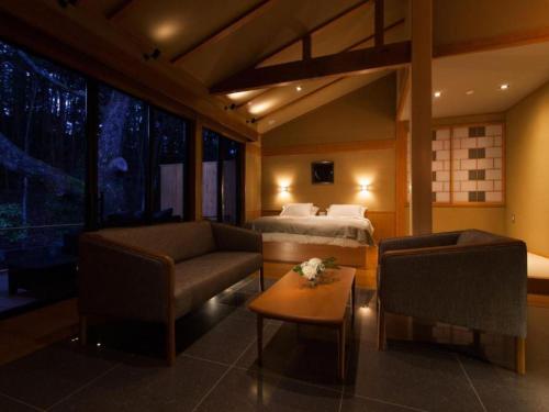 a hotel room with a bed and a couch and a table at Tsukiyominoza in Ise