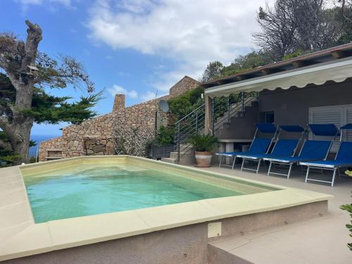 a large swimming pool with blue chairs and a house at VILLA ŚWISTAKKO in Costa Paradiso