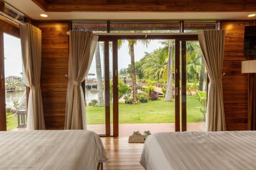 a bedroom with two beds and a large window at Rocks Beach Boutique in Phu Quoc