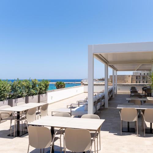 an outdoor patio with tables and chairs and the ocean at Hotel Bellavista - Boutique Hotel in Otranto