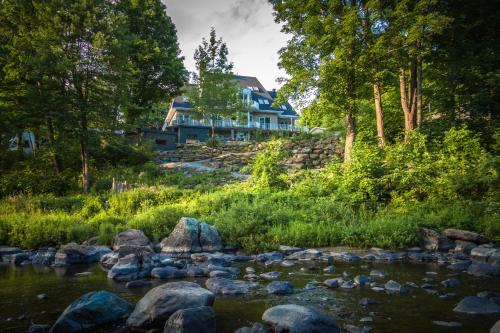 a house on a hill next to a river at Villa Nao in Roxton Falls