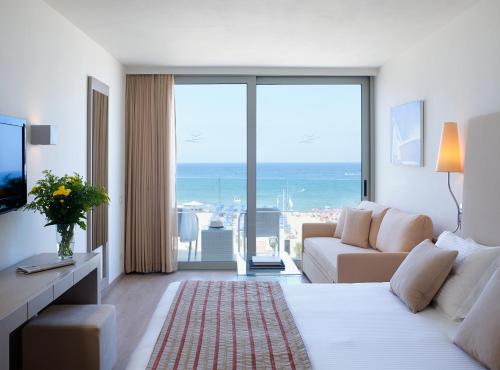 レティムノ・タウンにあるKriti Beach Hotelのベッドと大きな窓があるホテルの部屋