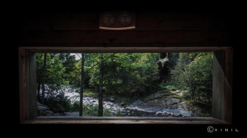 a window with a view of a river through a forest at Villa Nao in Roxton Falls