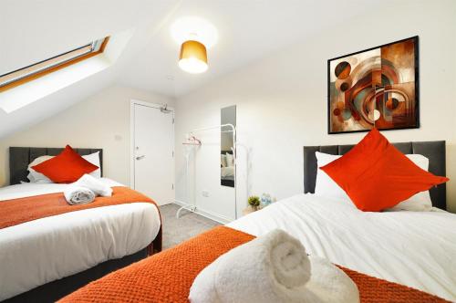 two beds with orange pillows in a bedroom at 3-Bedroom 5-Bed Flat King Room Free Parking Near Reading & M4 Work Stays in Shinfield