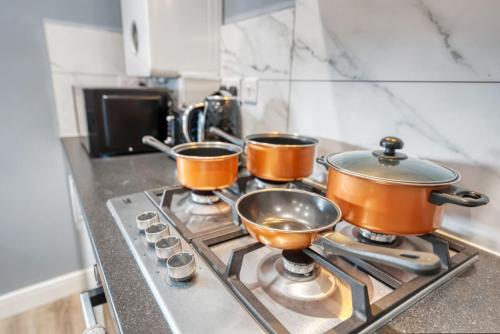 three pots and pans on a stove in a kitchen at 2 King or 4 Single Beds Workspace Walk to Bedford Station Parking Wi-Fi in Bedford