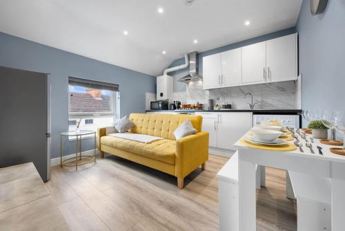 a living room with a yellow couch and a kitchen at 2 King or 4 Single Beds Workspace Walk to Bedford Station Parking Wi-Fi in Bedford