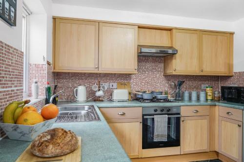 a kitchen with wooden cabinets and a counter top with a sink at Shops 4min walk Family 2 En-suite Parking x1 in Langley Marish