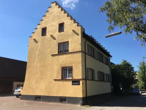 ein großes gelbes Gebäude mit spitzem Dach in der Unterkunft Altes Vogtshaus in Weil am Rhein