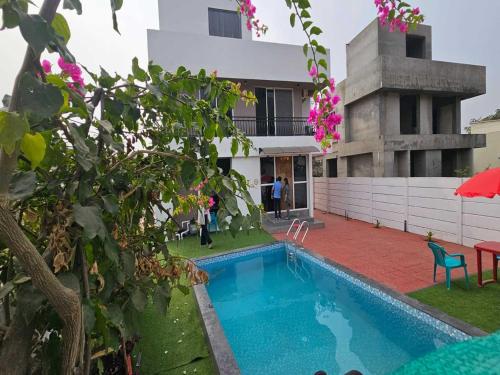 a house with a swimming pool in front of a building at Ventara Escape Bungalow by Palette Homes ? 4 BHK | Pvt Pool | Lonavala in Kārli