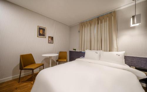 een hotelkamer met een groot bed en stoelen bij Tongyeong Daon Hotel in Tongyeong