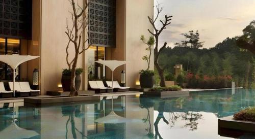 a swimming pool in a building with white chairs at Hotel Tentrem Yogyakarta in Yogyakarta