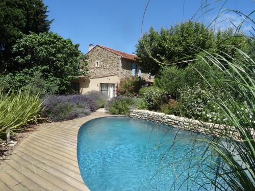 a swimming pool in a garden with a house at Le Nid de la Huppe in Noves
