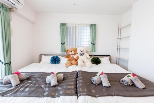 two teddy bears sitting on top of a bed at エンズプラザライカム1201 in Okinawa City