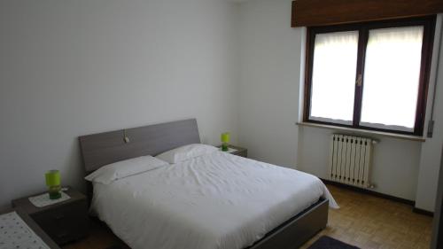 1 dormitorio con 1 cama blanca y 2 ventanas en Comodamente en Belluno