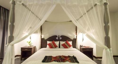 a bedroom with a white canopy bed with red pillows at Yeak Loam Hotel in Banlung