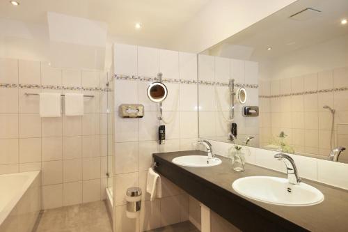 a bathroom with two sinks and a mirror and a tub at Gasthof zur Post Oberwirt in Chieming