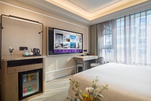 a hotel room with a bed and a flat screen tv at Mercure Xi'an History Museum in Xi'an