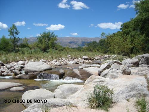 a river with rocks and waterfalls in a field at Cabañas La Curucucha in Nono