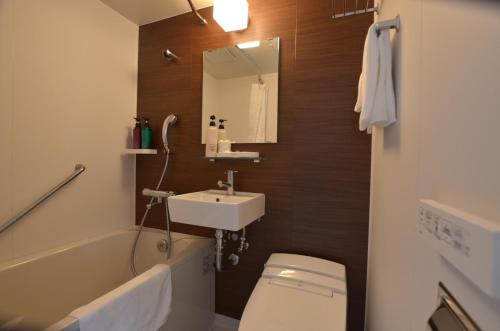 a bathroom with a sink and a toilet and a mirror at Isahaya Daiichi Hotel in Isahaya