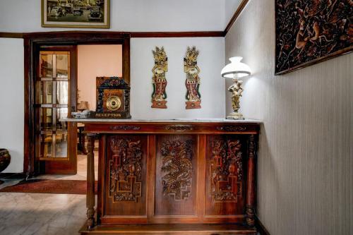 バンドンにあるHotel O Bandung near Stadion Siliwangi formerly The Ethnic Hotel Bandungの木製のキャビネットと壁に時計が備わる客室です。