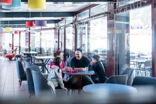 a man and two children sitting at a table in a restaurant at Villages Clubs du Soleil - LES KARELLIS in Montricher-Albanne