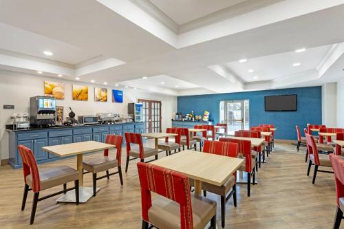 a restaurant with wooden tables and red chairs at Comfort Suites East Brunswick - South River in East Brunswick