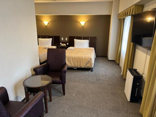 a hotel room with two beds and a table and chairs at GRG Hotel Naha in Naha