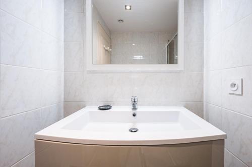 Un baño blanco con lavabo y espejo. en Appartement Aigueblanche, en La Lechere