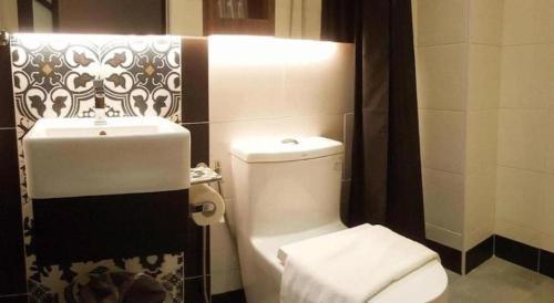 a bathroom with a white toilet and a sink at Styles Hotel in Melaka