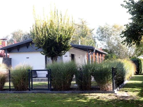 a fence in front of a house with tall grass at Holiday home, Luebben in Lübben