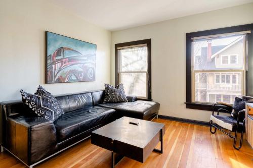 a living room with a black leather couch and a table at Stay Portland - Portland Classic - Walk to Local Coffee & Food in Portland