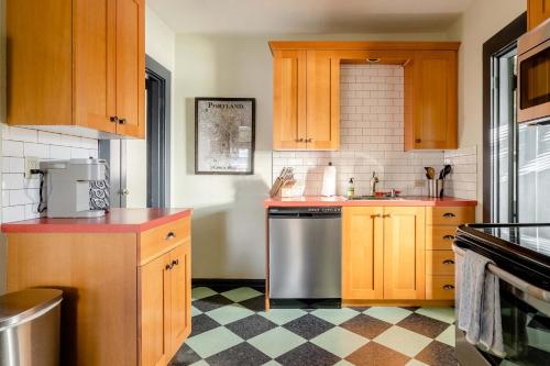 a kitchen with wooden cabinets and a stainless steel dishwasher at Stay Portland - Portland Classic - Walk to Local Coffee & Food in Portland