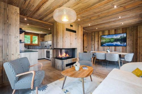 Una sala de estar con chimenea y una mesa y sillas. en Chalet Reine - Belle vue Mont-Blanc, en Combloux