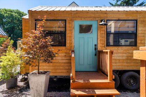 a wooden tiny house with a blue door at Stay Portland - Restored Farmhouse & Backyard Tiny House Village in Portland