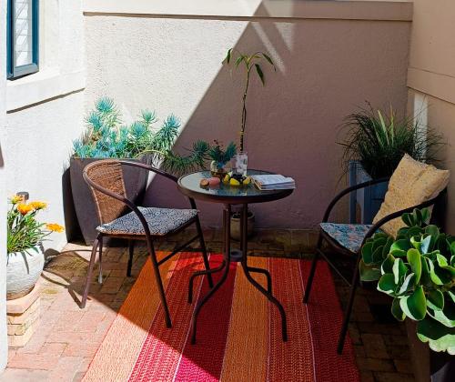 a small table and chairs on a patio with plants at Creative 2 Level Townhouse Near City and Wine Route in Brackenfell