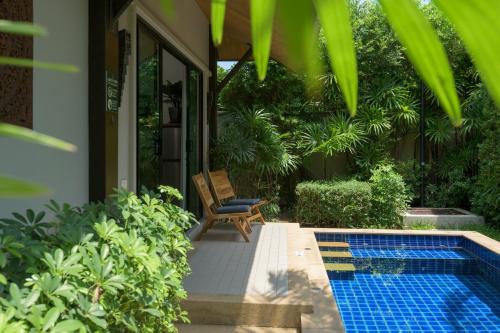 a patio with a chair next to a swimming pool at Green Garden Villa Hotel in Nai Harn Beach