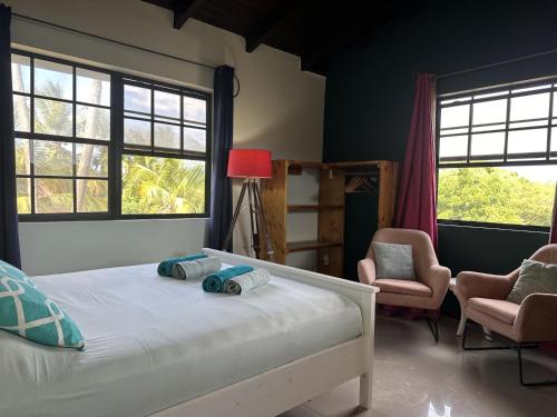 a bedroom with a bed and two chairs and windows at Woodstock Palmresort Curacao - Iguana Kamer in Santa Catharina