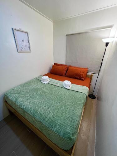 une petite chambre avec un lit avec des draps orange et verts dans l'établissement Caalan Cottage, à El Nido