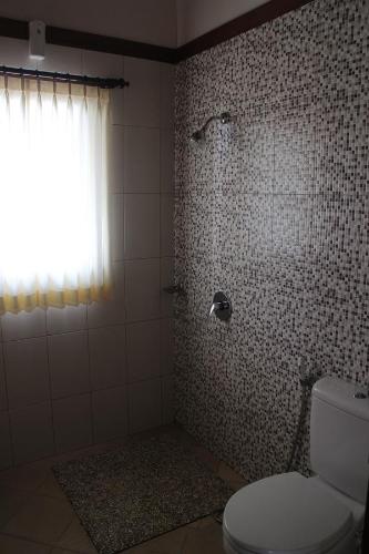 a bathroom with a shower with a toilet and a window at Betutu Bali Villas in Ubud