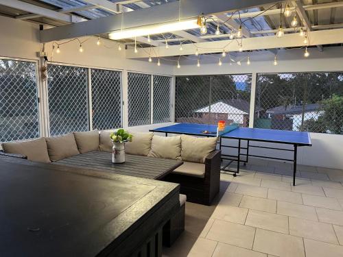 a patio with a couch and a ping pong table at The Waratah Escape Nowra in Nowra