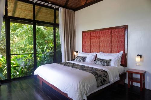 a bedroom with a white bed with a large window at Hidden Gardens Resort, Davao in Davao City