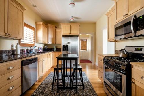 une cuisine avec des armoires en bois et un comptoir noir dans l'établissement Stay Portland - Sun-filled Home in Buckman Neighborhood with 2BRs, à Portland