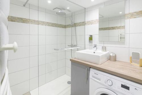 ein weißes Badezimmer mit einem Waschbecken und einer Waschmaschine in der Unterkunft Beau studio rénové, balcon, accès plage, piscine in Biarritz