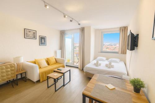 ein Wohnzimmer mit einer Couch, einem Bett und einem Tisch in der Unterkunft Beau studio rénové, balcon, accès plage, piscine in Biarritz