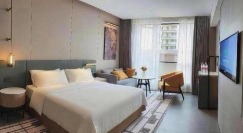 a bedroom with a large bed and a living room at Four Points by Sheraton Haikou International Airport in Haikou