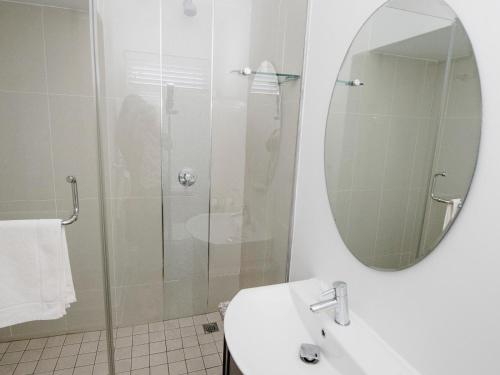 a bathroom with a shower and a sink and a mirror at Bateleur Guesthouse in Klerksdorp