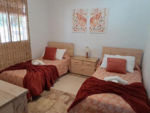 a bedroom with two beds and a table and a window at El Higuerón (Serranía de Ronda) in Jimera de Líbar