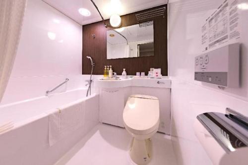 a white bathroom with a toilet and a tub and a sink at Nagoya Sakae Tokyu REI Hotel in Nagoya